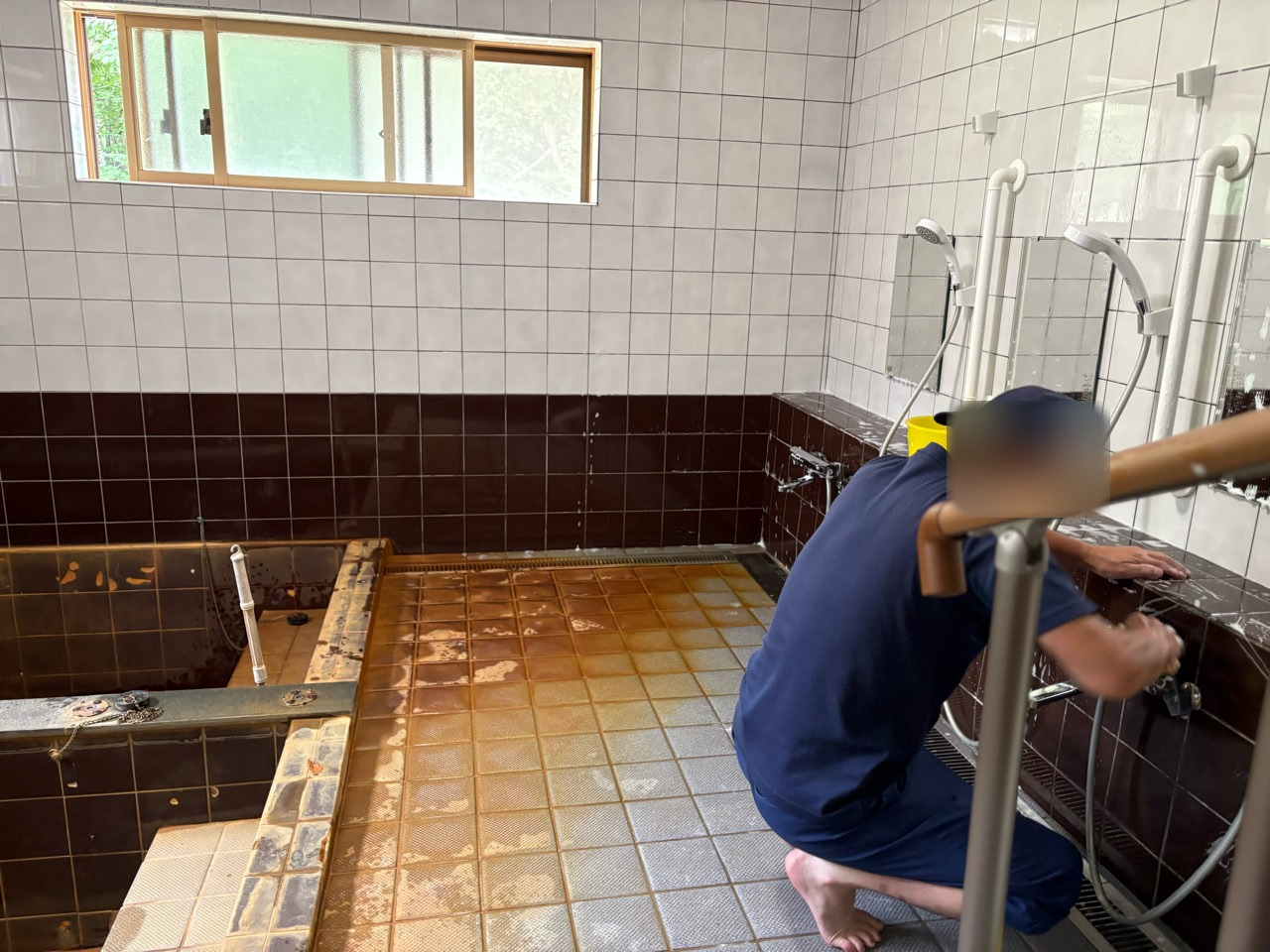 受託した清掃の仕事で、浴室の水栓まわりを手入れする様子