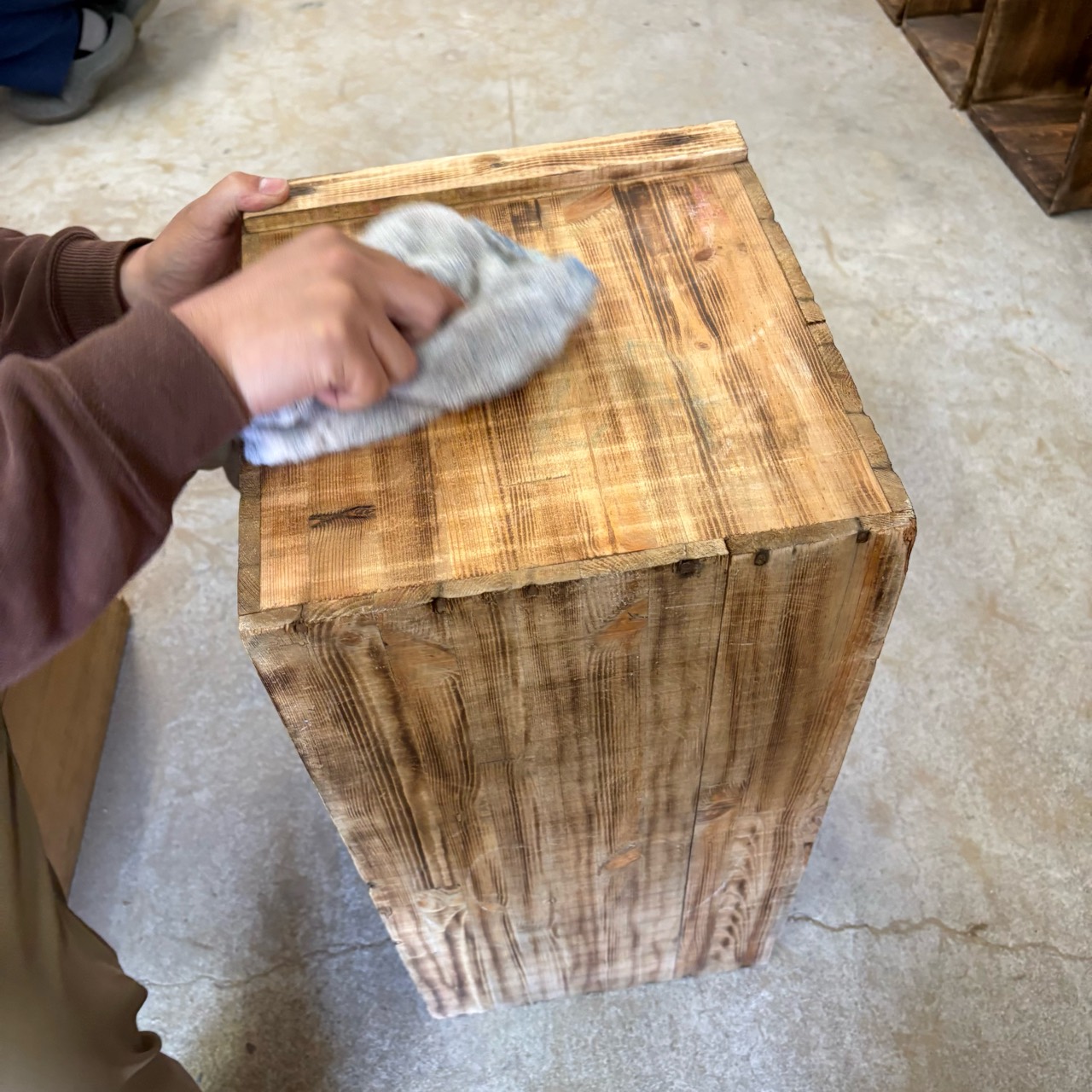 木箱の表面を布で拭く手元